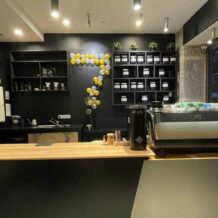 La barra interior de Bocono Specialty Coffee con un barista preparando un café especial y una amplia variedad de granos de café y tazas de cerámica en exhibición