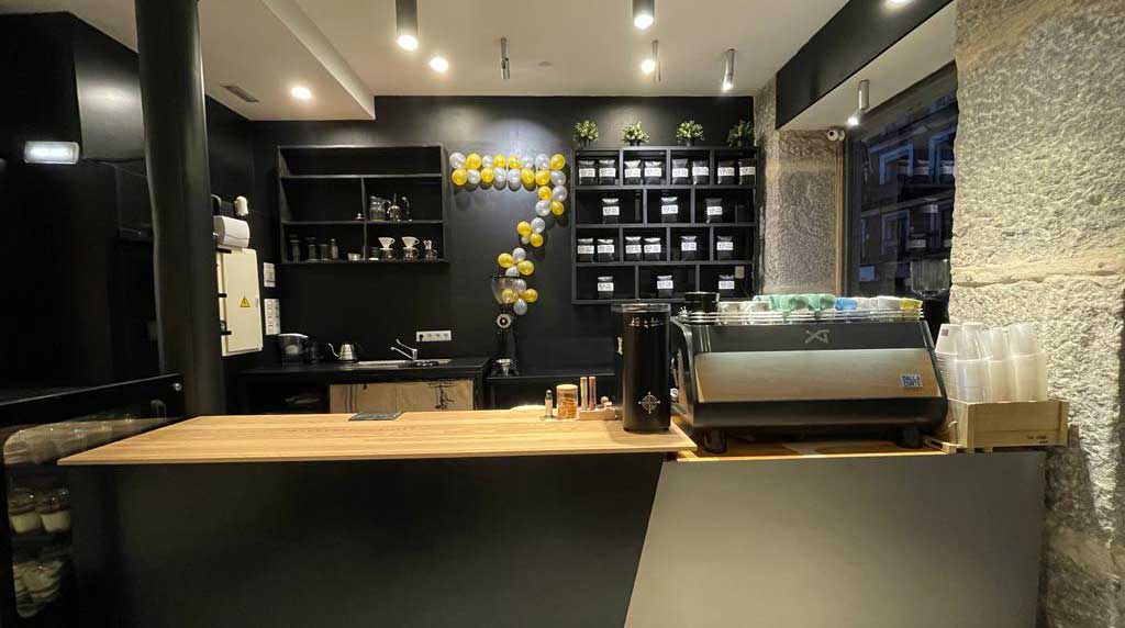 La barra interior de Bocono Specialty Coffee con un barista preparando un café especial y una amplia variedad de granos de café y tazas de cerámica en exhibición