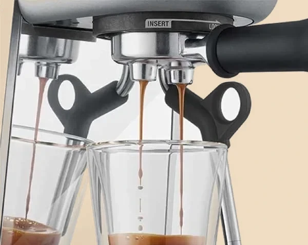 Dos chorros de espresso caen del portafiltros de la Sage Bambino en dos vasos de cristal