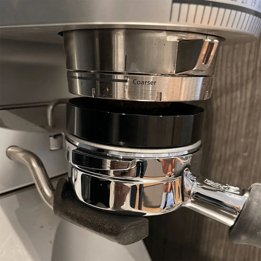 Embudo dosificador sobre el portafiltros, recogiendo el café que sale del molinillo