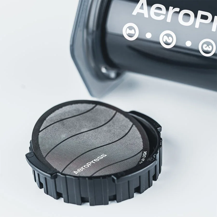Filtro metálico estándar AeroPress dentro de la tapa apoyada sobre la cafetera