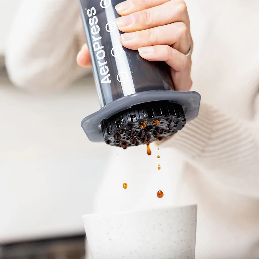 AeroPress Original sobre una taza, con el café goteando por la tapa del filtro