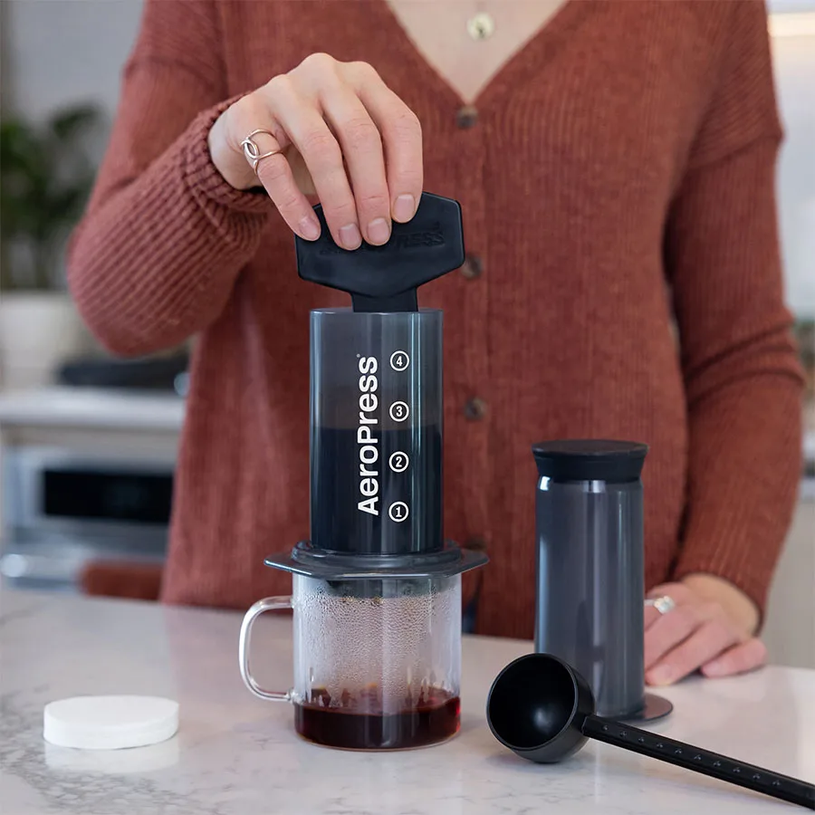 Preparando café en casa con la AeroPress Original, su cuchara dosificadora y una jarra