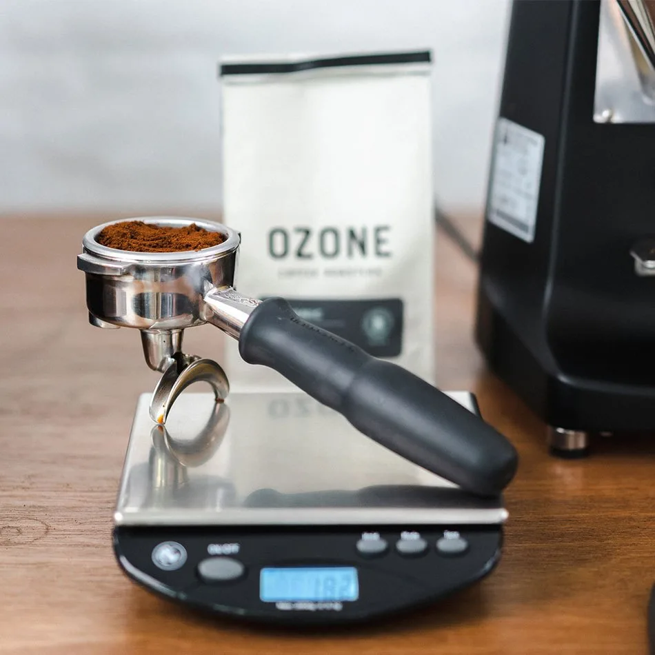 Portafiltros con café recién molido sobre una báscula de 0,1 g, junto al molinillo