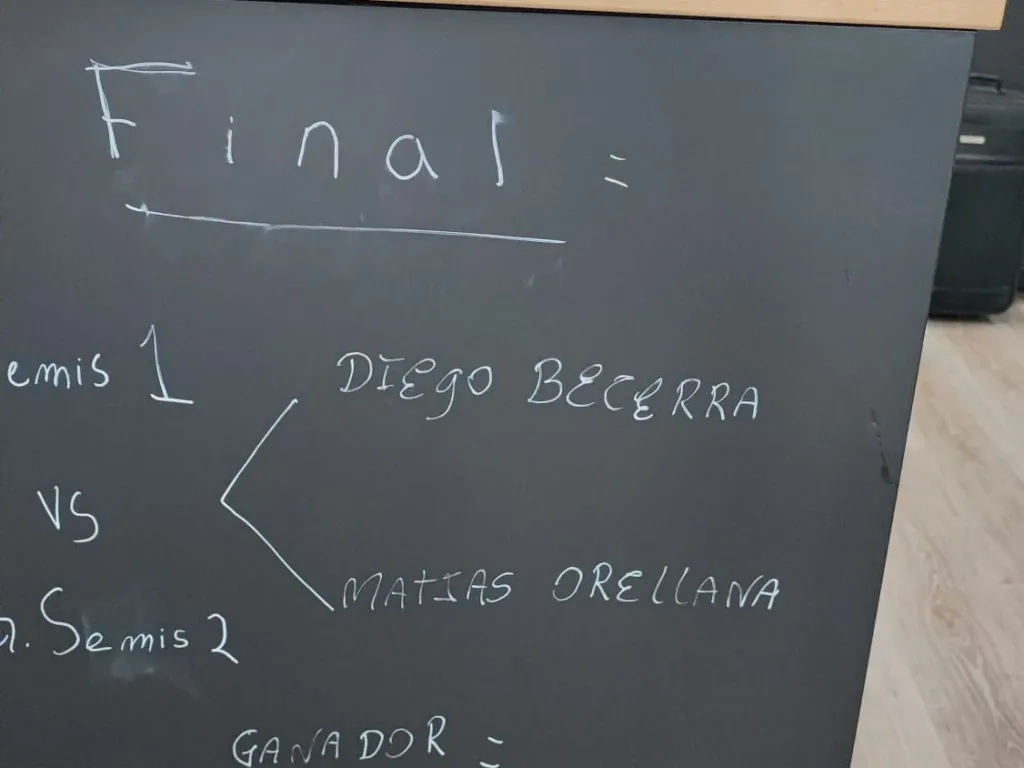 Pizarra negra con el cuadro de la final escrito a tiza, desde las semifinales hasta el ganador.