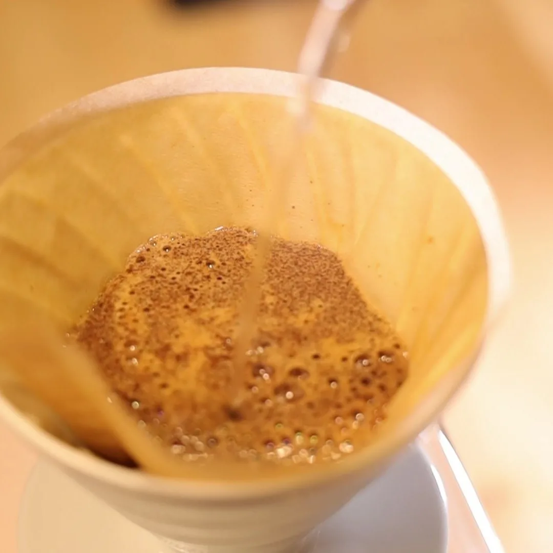 Café en floración con burbujas dentro del Hario V60 02 blanco
