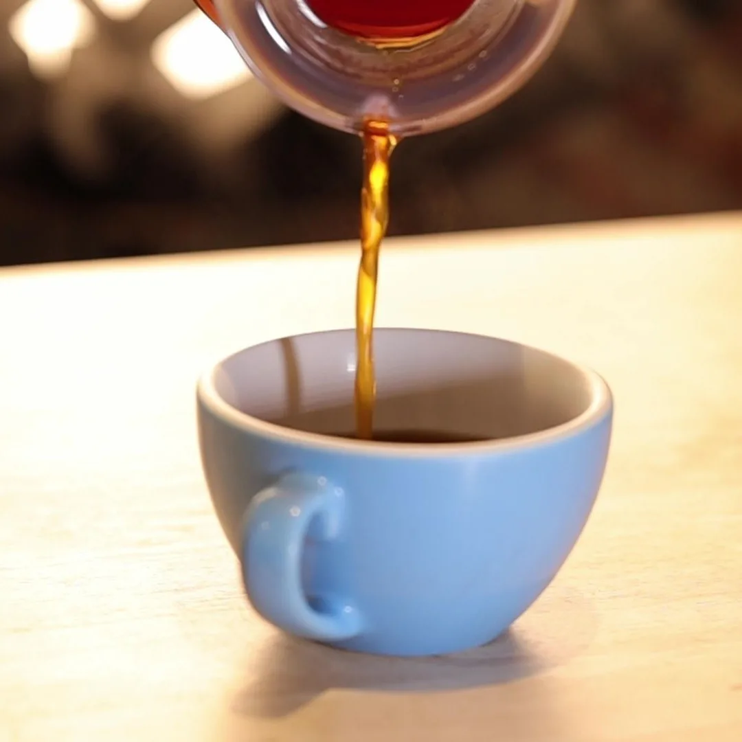 Café preparado con el Hario V60 02 blanco cayendo en una taza azul