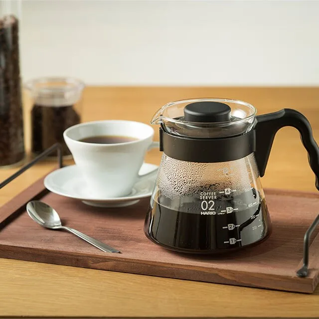 Hario V60 Coffee Server 700 ml con café en una bandeja de madera junto a una taza
