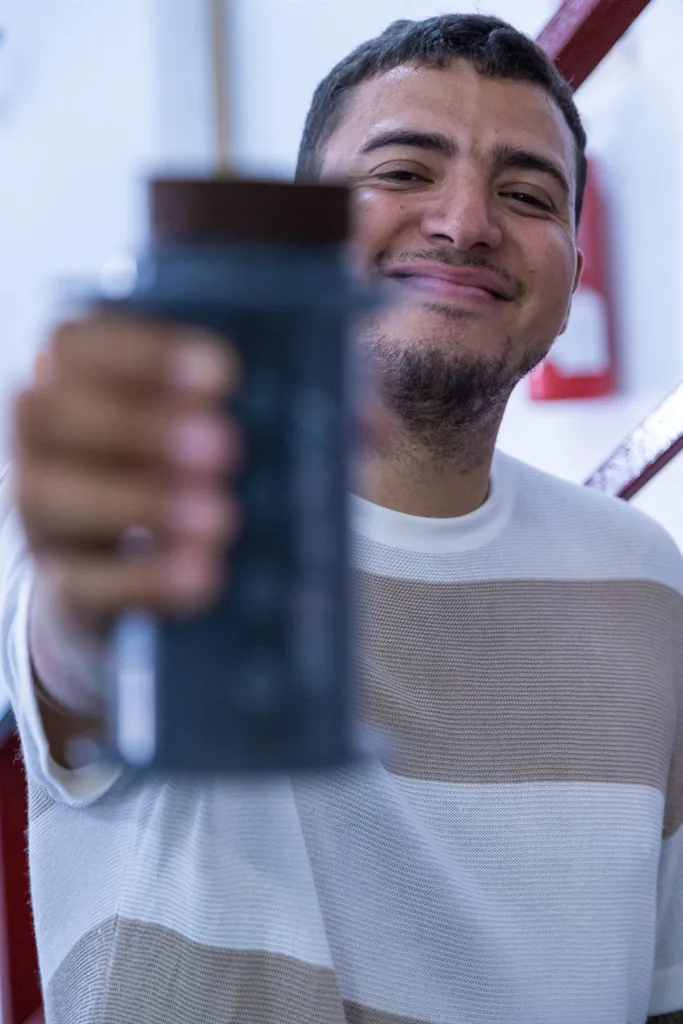 Competidor sonriendo mientras levanta su AeroPress hacia la cámara