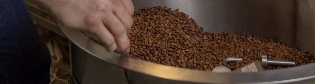 Carlos Núñez remueve con la mano el café de especialidad recién tostado en la bandeja de enfriado del tostador de Boconó