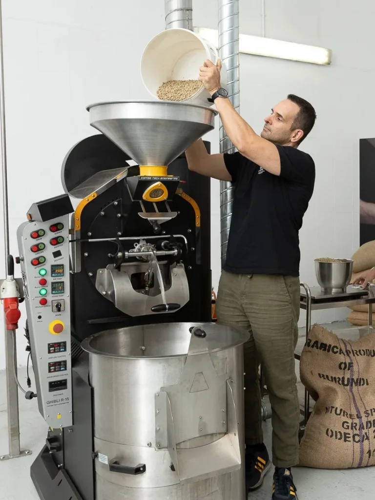 Carlos Núñez vierte café verde en la tolva del tostador Coffee-Tech, en el tostadero de Boconó en Madrid