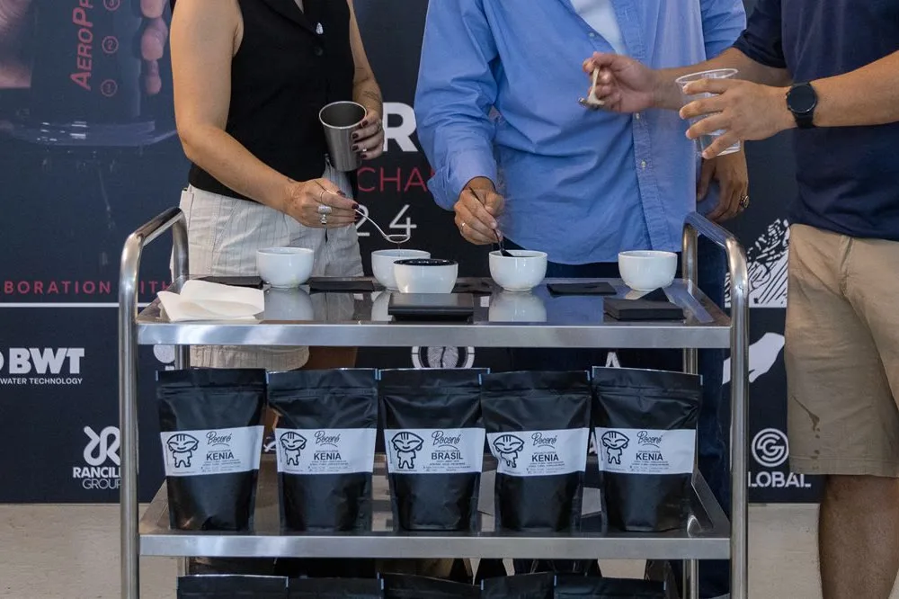 Tazas y cucharas de cata sobre un carrito de acero en el tostadero de Boconó, con bolsas de café en la balda de abajo