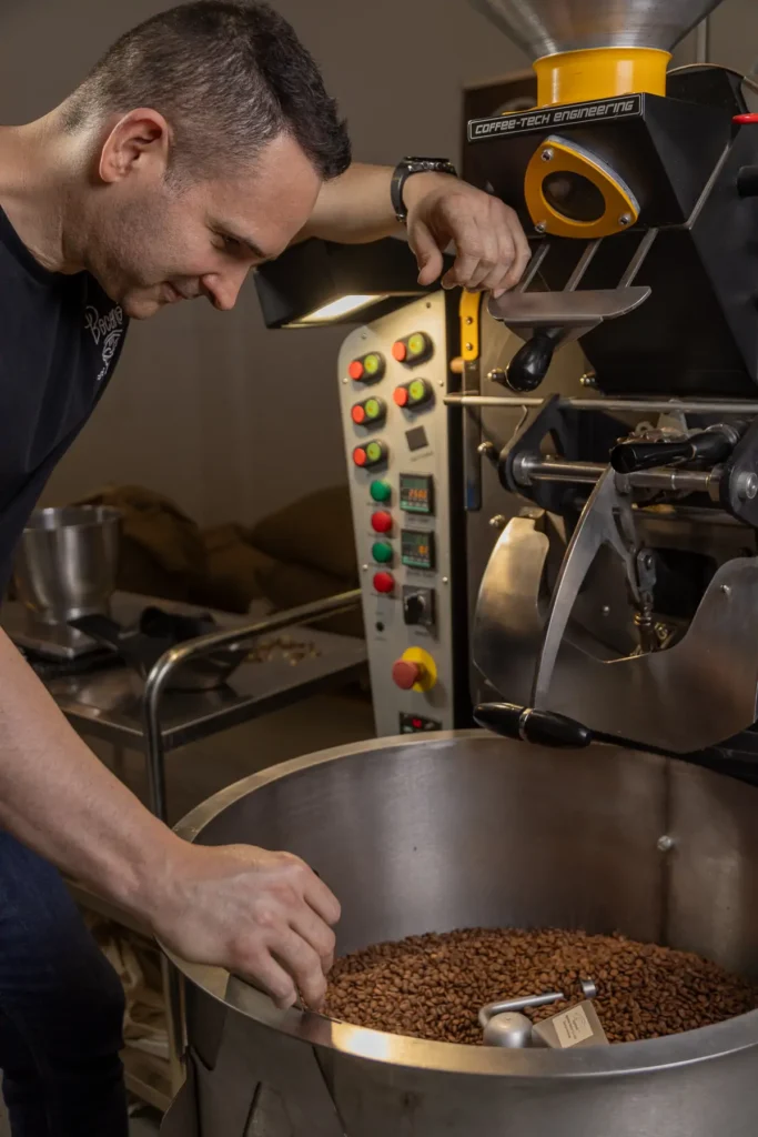 Carlos Núñez remueve con la mano el café recién tostado en la bandeja de enfriado del tostador de Boconó, en Madrid