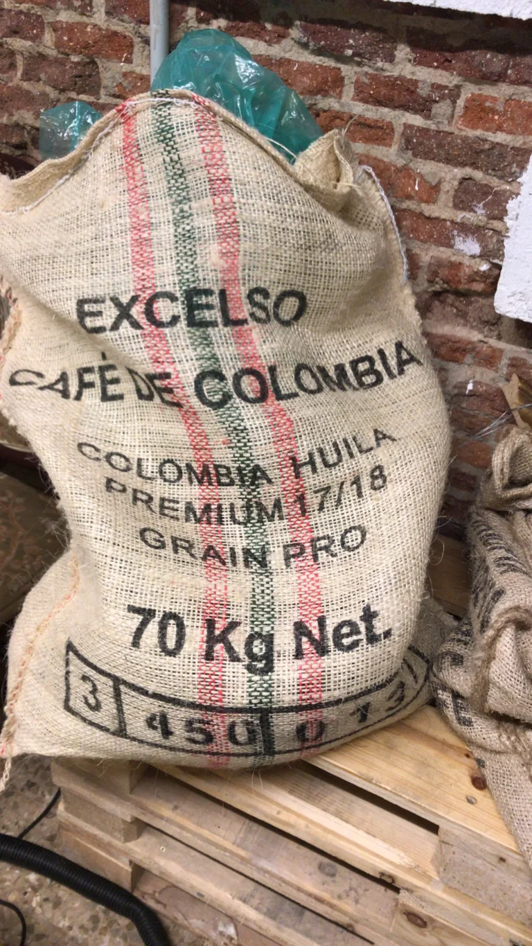 Saco de yute de 70 kilos de café verde «Excelso Café de Colombia, Colombia Huila Premium 17/18», sobre un palé junto a la pared de ladrillo del tostadero de Boconó, en abril de 2018