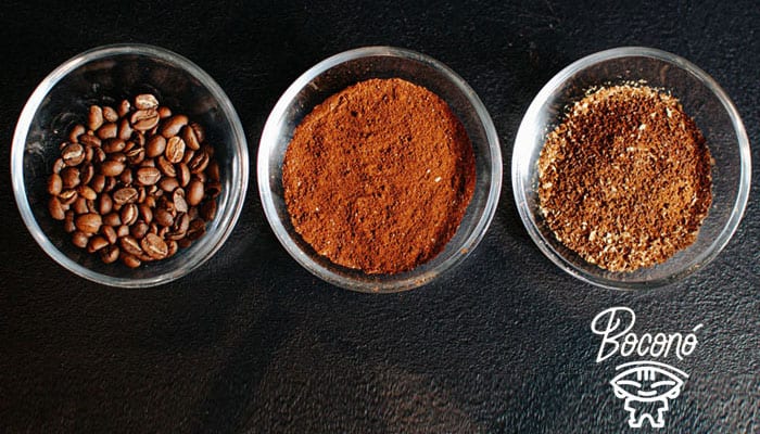 Tres cuencos de cristal sobre fondo negro: café en grano, café molido fino y café molido grueso