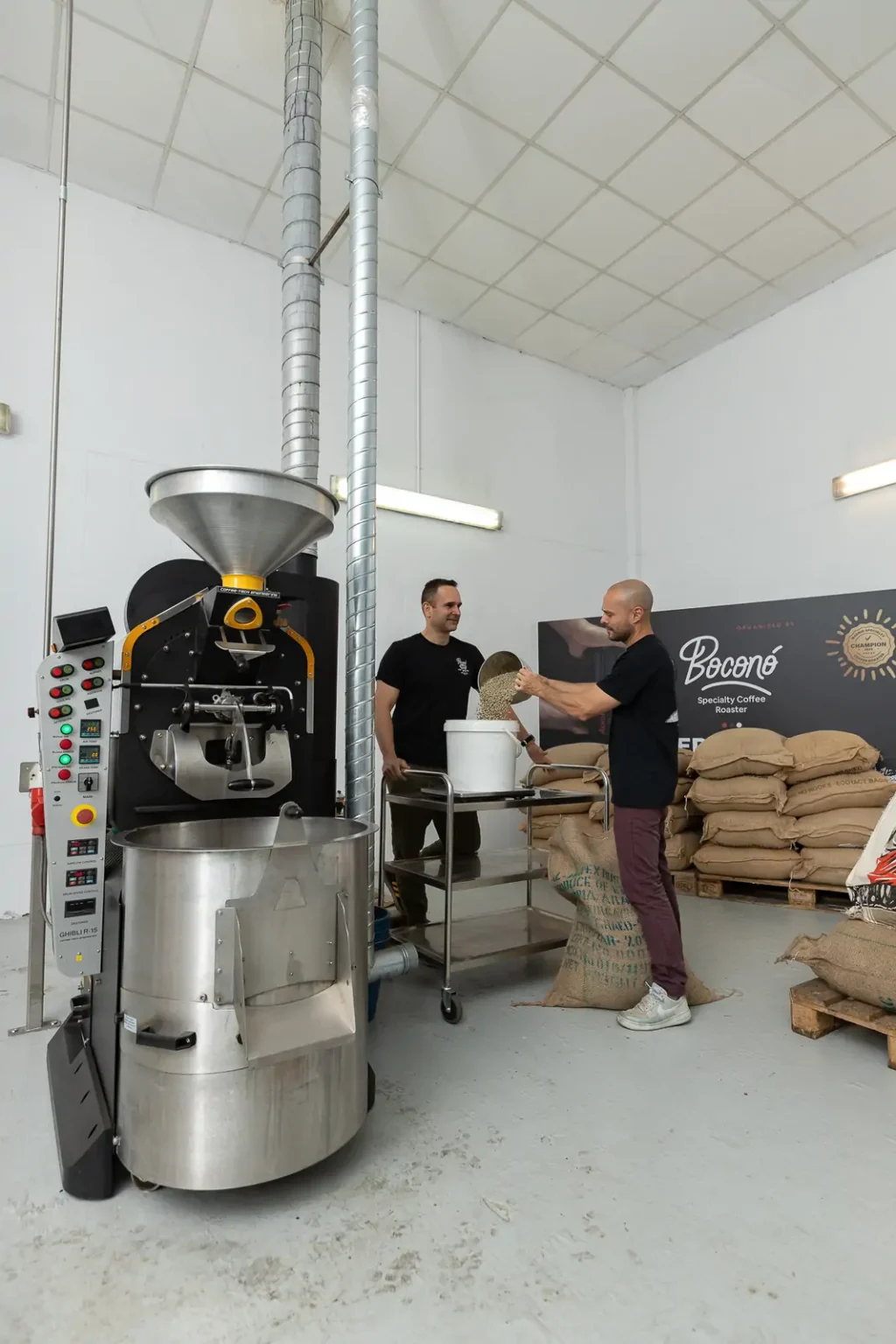 Carlos Núñez y Gastón Saldivia, los dos tostadores de Boconó, preparan el café verde junto a la tostadora del tostadero de Madrid, con los sacos de café detrás