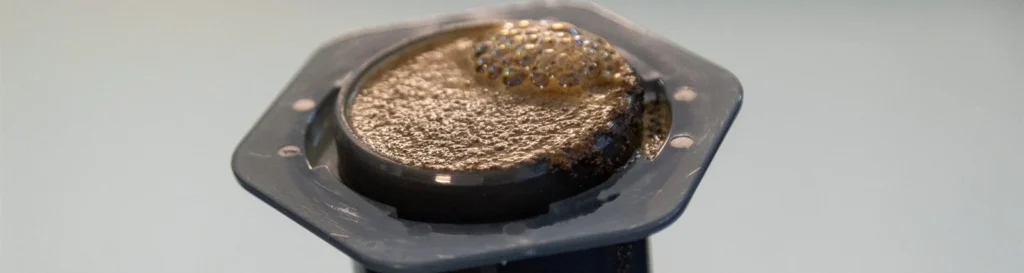 Pastilla de café molido comprimida en la cámara de una AeroPress después de preparar el café