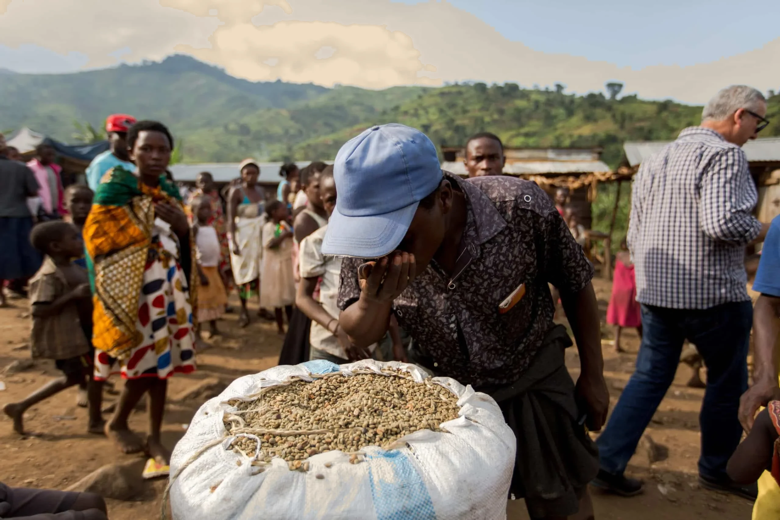 Corro de vecinos alrededor de un saco abierto de café en pergamino en una aldea de Kasese, en la región del Rwenzori (Uganda)