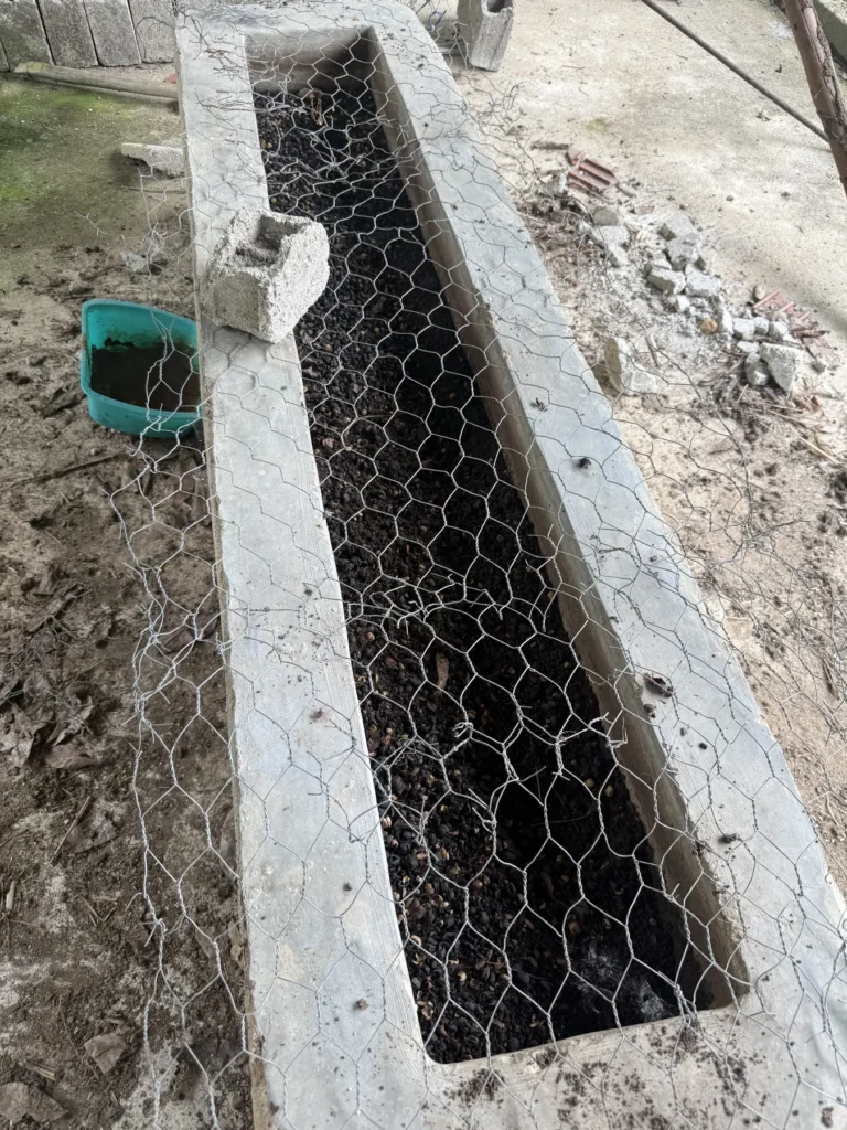 Cantero de obra alargado cubierto con malla metálica donde se cría la lombriz para transformar la pulpa de café, en una finca de Zea