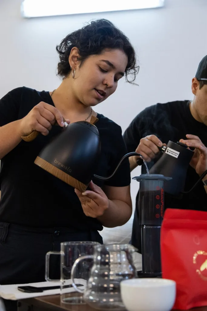Competidora sirviendo el café recién extraído en la taza de cata