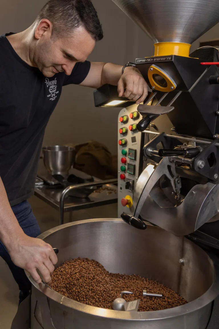 Manos removiendo el café recién tostado en la bandeja de enfriado del tostadero de Boconó