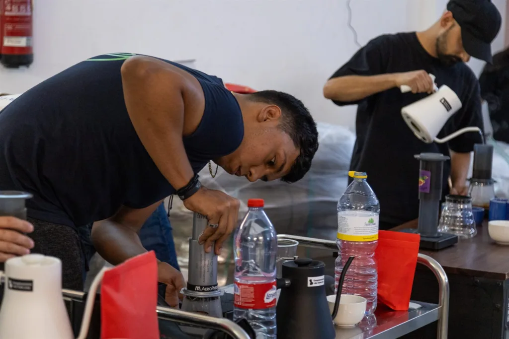 Competidor prensando el émbolo de la AeroPress con las dos manos sobre una taza