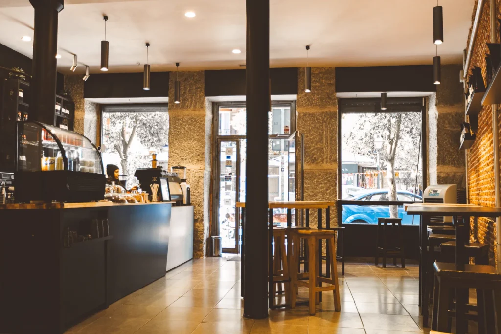 Interior de la primera cafetería de Boconó en Madrid, en Lavapiés, con la barra, las ventanas a la calle y las mesas altas de madera