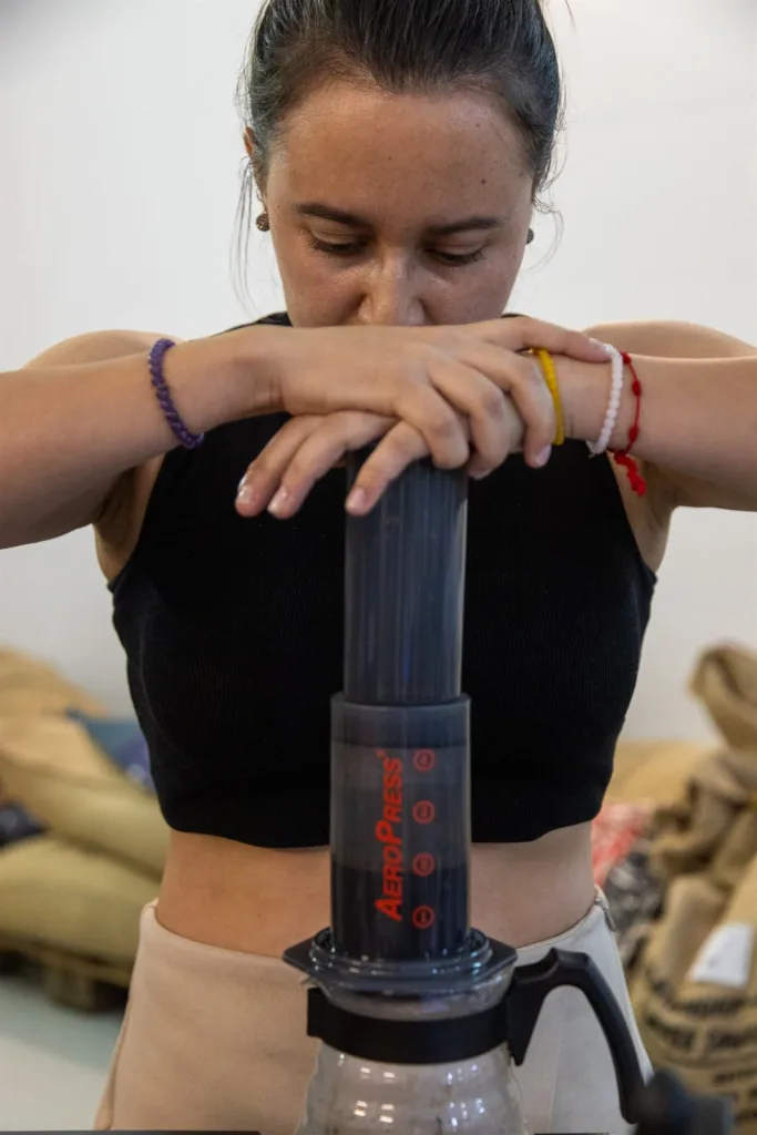 Competidora empujando el émbolo de la AeroPress con el peso del cuerpo