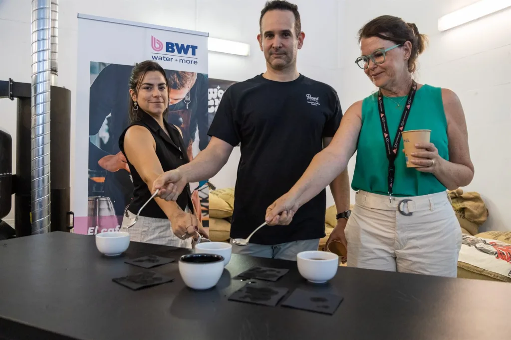 Jueces con cucharas de cata sobre las tazas antes de probar