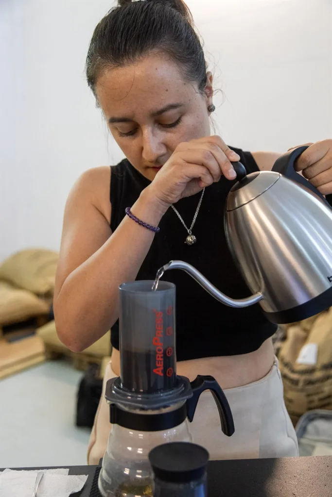 Competidora vertiendo agua con un hervidor de cuello de cisne dentro de la AeroPress