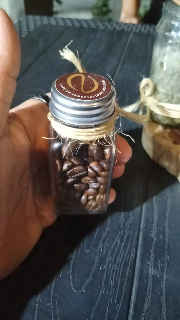 Frasco de cristal con granos de café tostado de una finca de Boconó, sostenido en la mano
