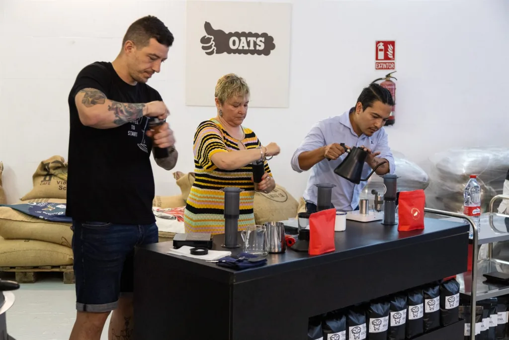 Tres personas preparando café con AeroPress a la vez en la misma mesa durante una ronda