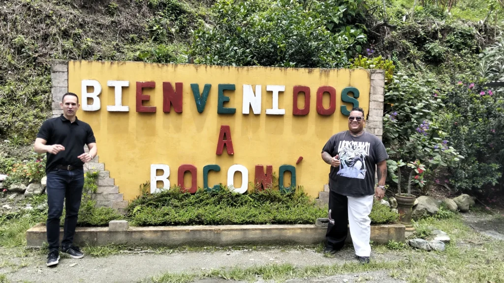 Carlos Núñez y Francisco Soto junto al cartel de bienvenida a Boconó, estado Trujillo, Venezuela, en abril de 2026